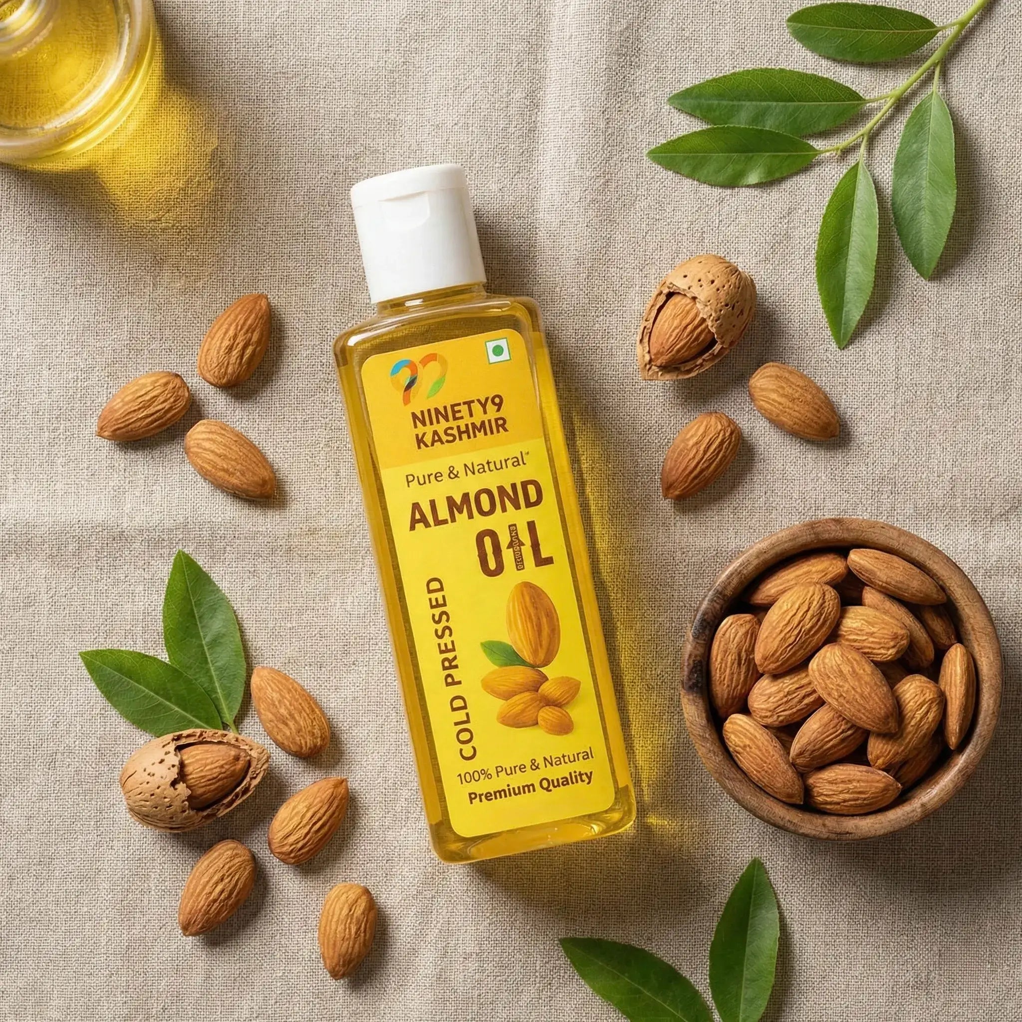Bottle of Kashmiril's almond oil with almonds and leaves on a textured surface
