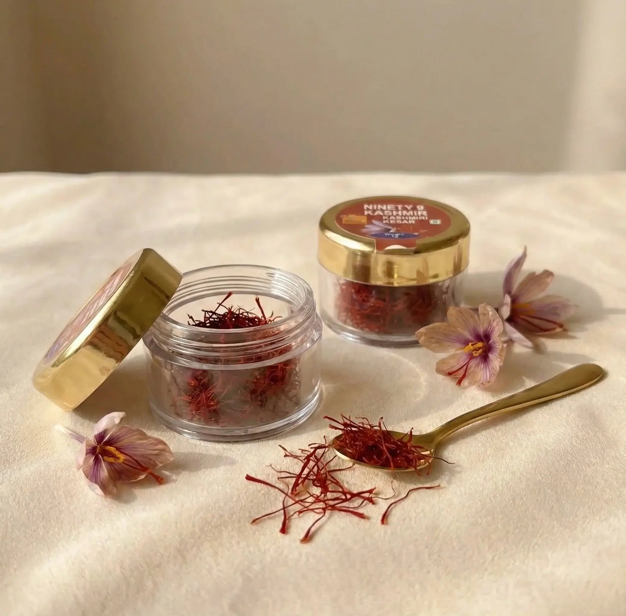 Jars of saffron with a spoonful on a white surface